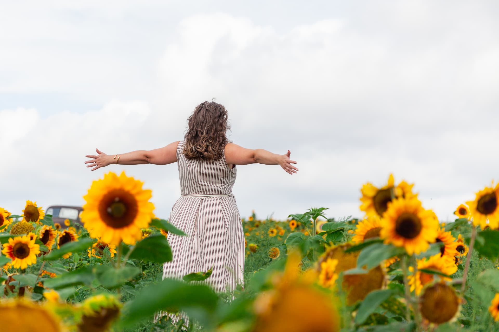 Kate Keir standing with her arms outstretched in a sunflower field